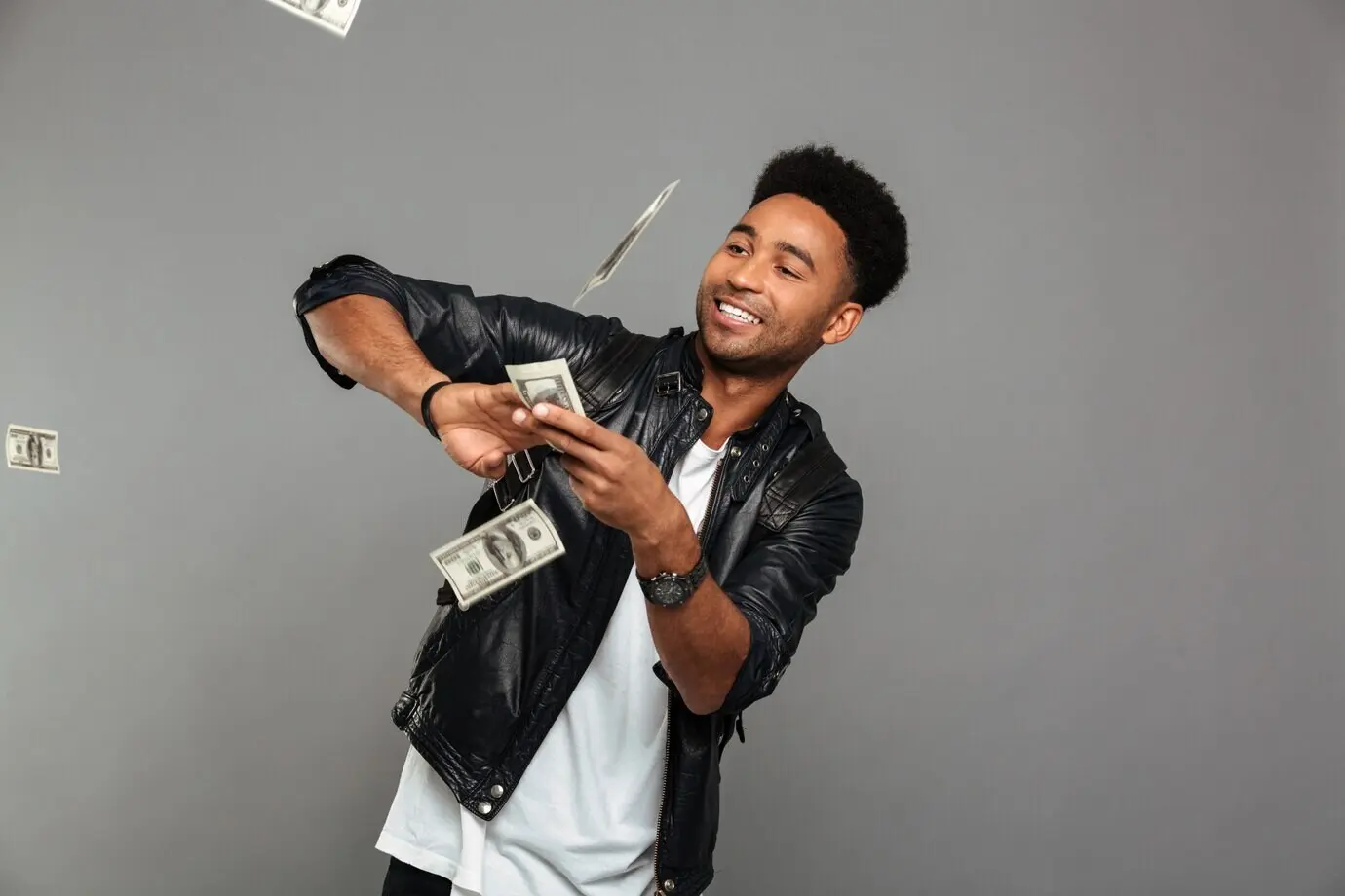 Hombre afroamericano rico y gracioso esparciendo billetes de dólar
